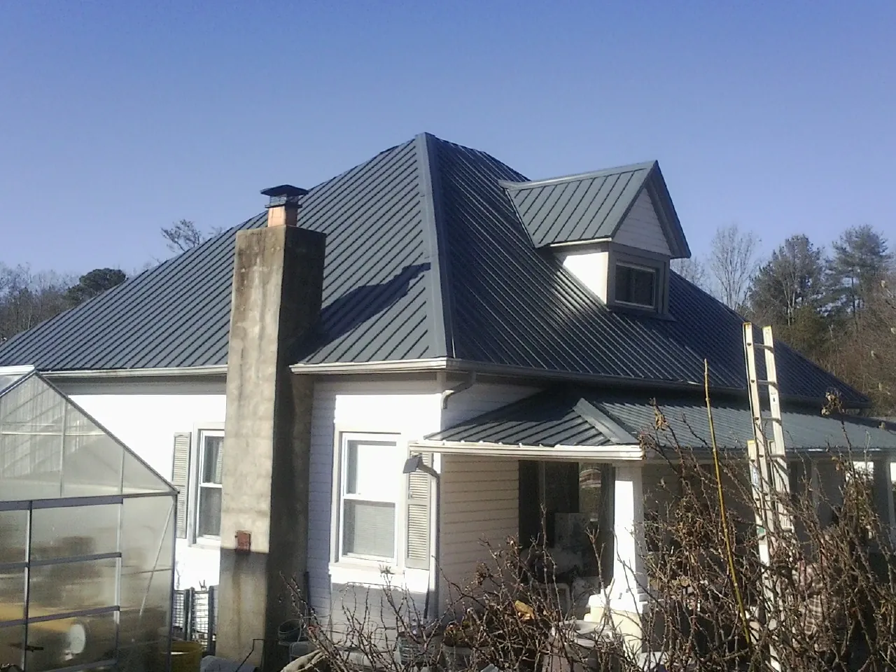 Dark blue standing seam metal roof on a white farmhouse with dormer — Slate & Tile Roof Repair by Roofing Brothers in West Bridgewater