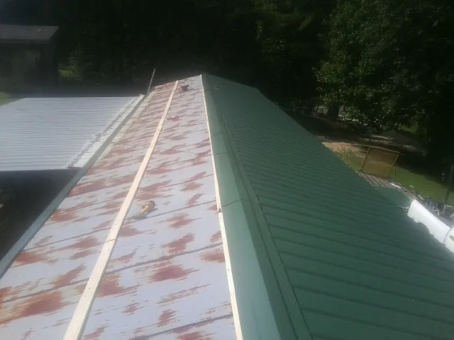 Old rusted panels beside newly installed green metal roofing — Wind Damage Roof Repair by Roofing Brothers in West Bridgewater