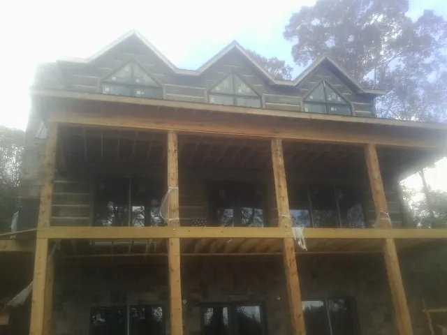 Dormers and porch framing on a large log home under construction — Roof Coating work by our crew in West Bridgewater