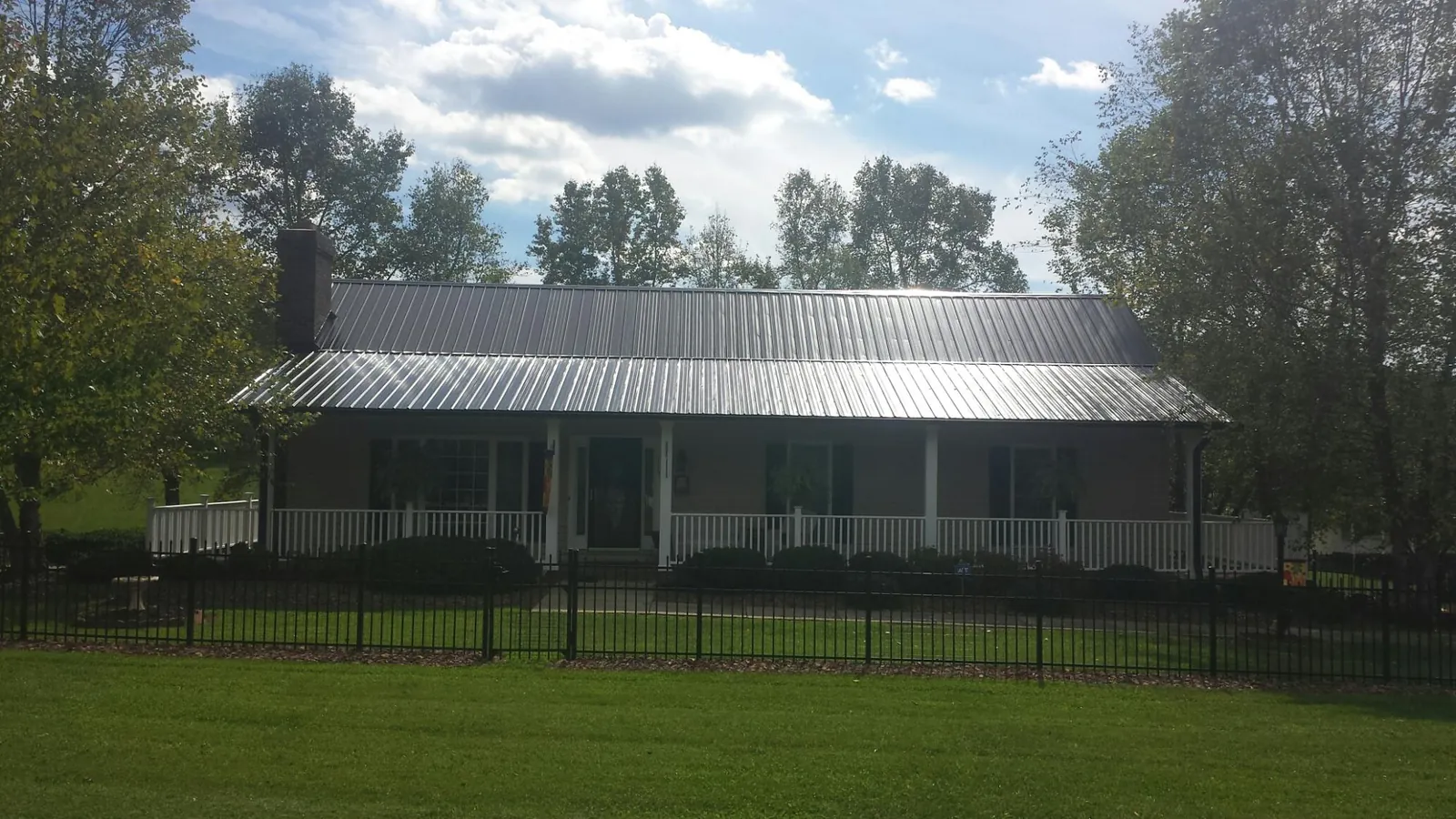 Gray metal roof on a brick ranch with a full width front porch — Gutter Guard Installation work by our crew in West Bridgewater