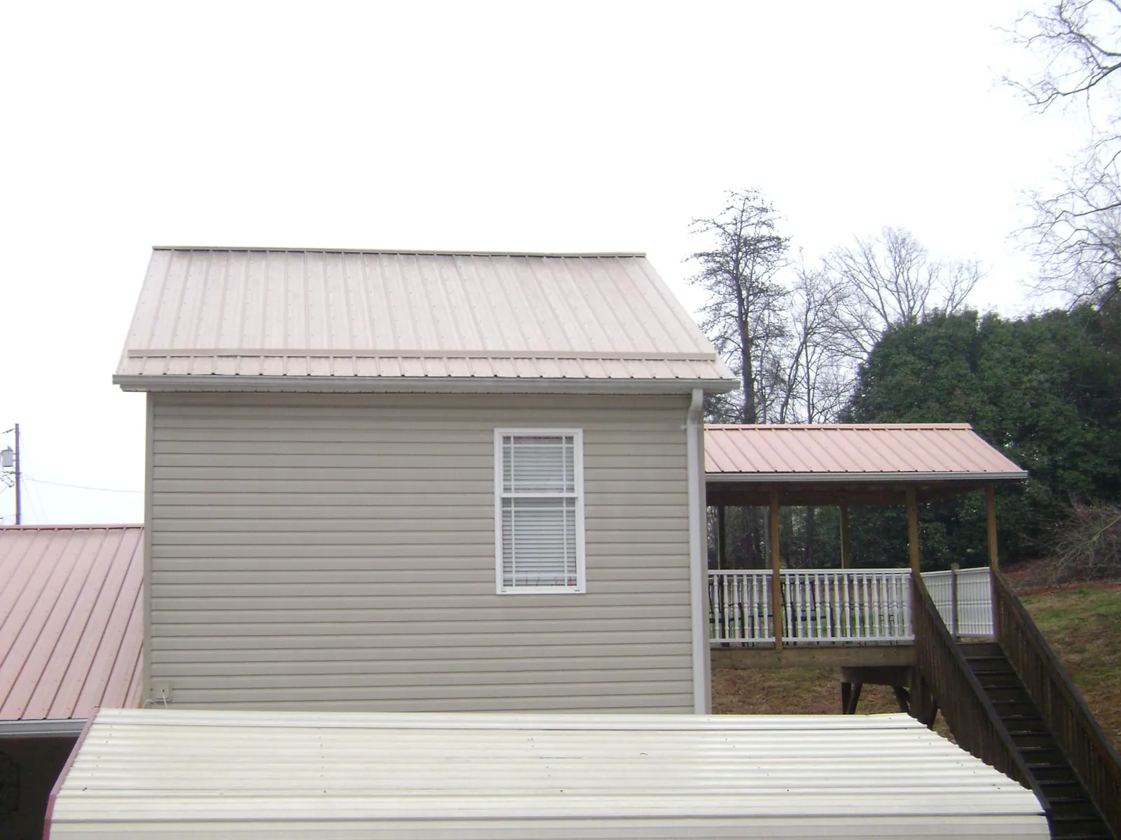 Tan metal roofs on a two story addition and attached porch, from a Roof Replacement job in West Bridgewater