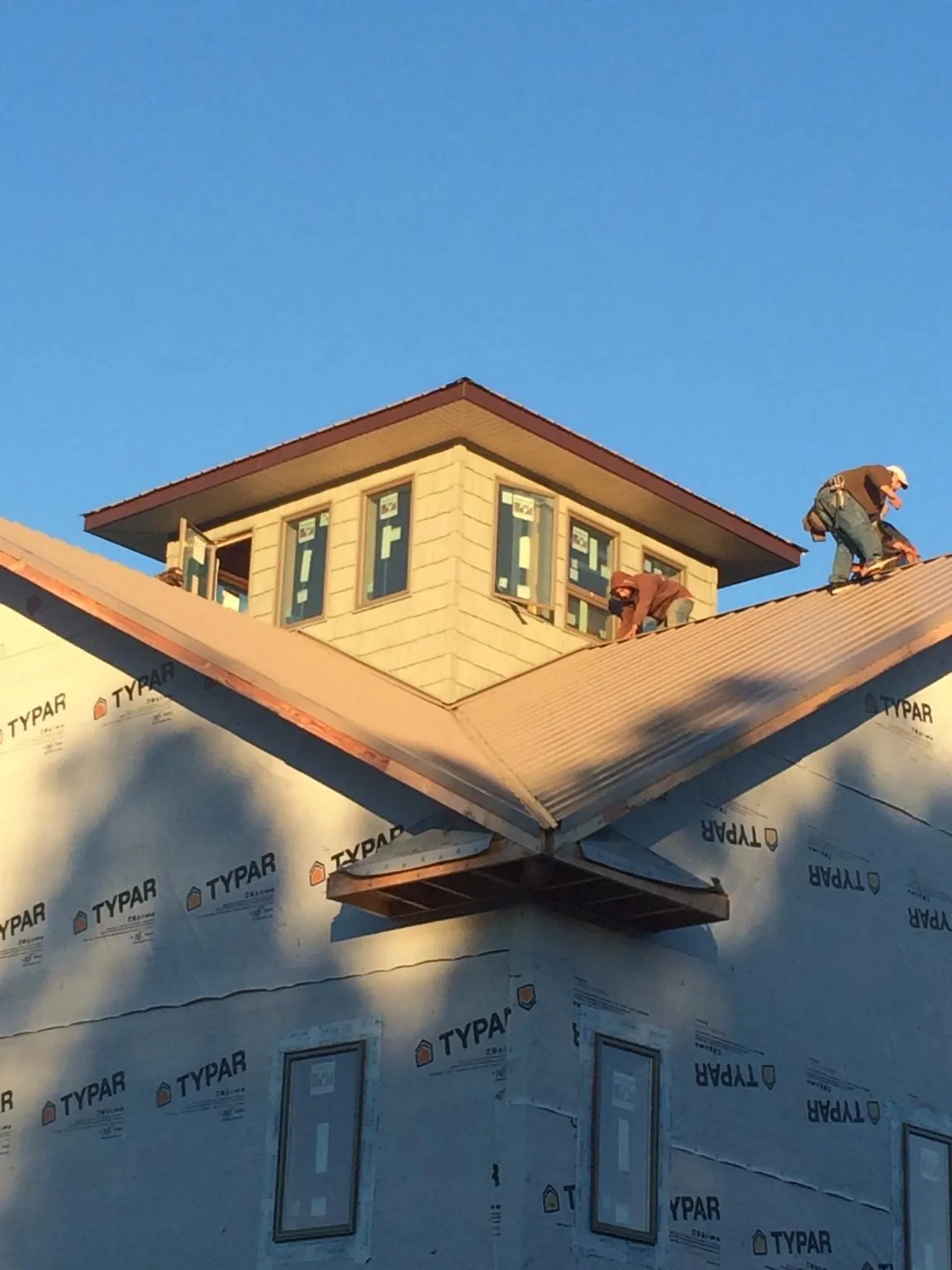 Roofers working around a rooftop cupola on a new metal roof at sunset — Roof Waterproofing in West Bridgewater by Roofing Brothers